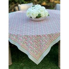 a pink and white table cloth on top of a wooden table with flowers in it