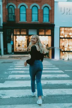 a woman standing in the middle of a crosswalk with her hands behind her back