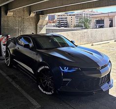 a black chevrolet camaro is parked under an overpass