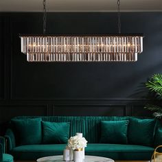 a living room with green couches and a chandelier hanging from the ceiling