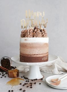 a birthday cake sitting on top of a white cake platter next to coffee beans