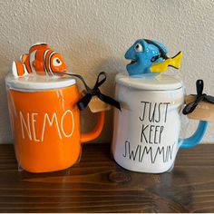 two ceramic mugs with fish on them sitting next to each other and the words nemo painted on them