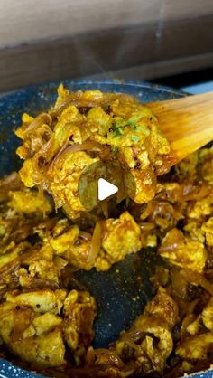 food being cooked in a blue bowl with a wooden spoon