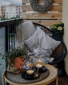 a table with candles on top of it next to a chair and a wreath hanging from the wall