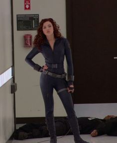 a woman in a black cat suit standing next to a door