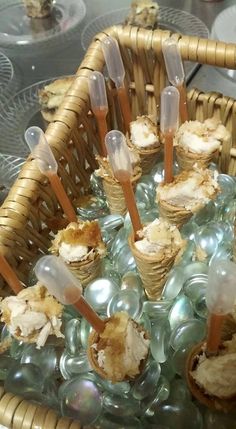 there are many ice cream cones in the basket with plastic spoons on top of them