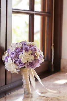 a bouquet of purple and white flowers sitting on top of a counter next to a window