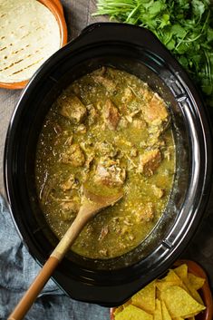 a bowl filled with chicken and spinach soup next to tortilla chips on the side