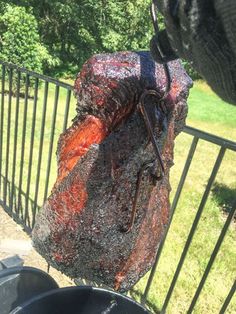 a hand holding a bag that is covered in red and black stuff next to a trash can