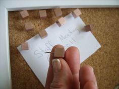 a person holding a tiny piece of wood in front of a sign with words on it