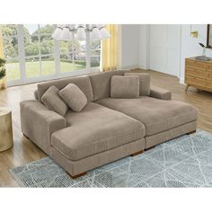 a living room with a large sectional couch in the center and a rug on the floor