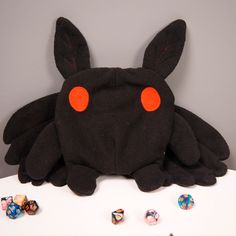 a stuffed animal with red eyes sitting on top of a table next to some dice