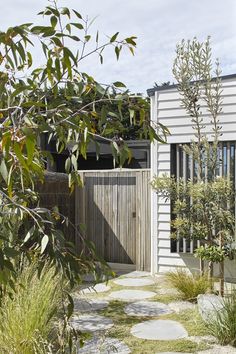 a house with a wooden gate surrounded by plants