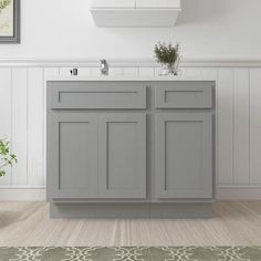 a white bathroom with gray cabinets and a green rug on the floor in front of it