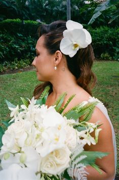 a woman holding a bouquet of white flowers in her hand and looking off into the distance