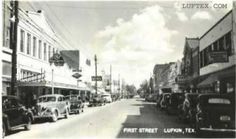 an old black and white photo of cars parked on the street