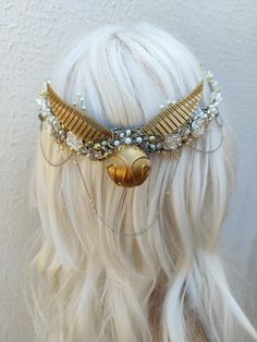 a blonde wig wearing a gold and white headpiece with an owl on it's side