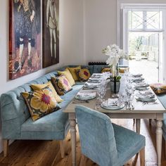 a dining room table with blue couches and plates on it