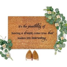 a pair of shoes sitting next to a door mat with the words it's the possibilities of having a dream come true that makes life interesting