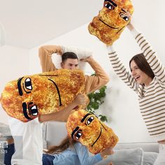 two people holding up pillows with faces on them