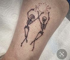 a tattoo on the leg of a person with two skeletons and stars in their hands