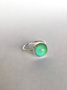 "This ring features a 10mm round Mood stone bezel set in a handmade serrated bezel. The mood stone changes colors varying from yellow, green, blue, and purple! **PLEASE NOTE the gold-fill option features a plain bezel, instead of a serrated bezel (the part that wraps around the stone This ring is made to order and can be made in any size or material! If what you're looking for is not listed in the dropdown menus, just message me! *Mood \"stones\" are man-made from acrylic and unlike gemstones mi Minimalist Iridescent Round Jewelry, Handmade Green Jewelry With Round Stone, Modern Green Round Band Jewelry, Green Round Minimalist Jewelry, Green Minimalist Round Jewelry, Modern Green Cabochon Jewelry, Green Jewelry With Bezel Setting And Round Band, Iridescent Gemstone Jewelry, Iridescent Round Gemstone Jewelry