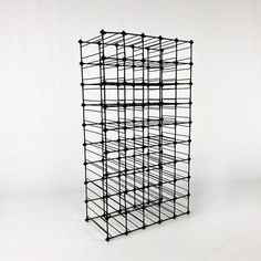 a black metal structure with lots of wires attached to the top and bottom part, against a white background