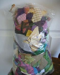 a large bag filled with lots of different colored pieces of cloth on top of a wooden table