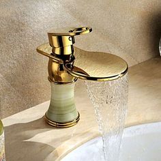 a gold faucet with water running from it's spout in a bathroom sink