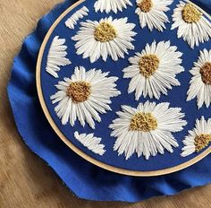 a blue plate with white daisies on it sitting on top of a wooden table