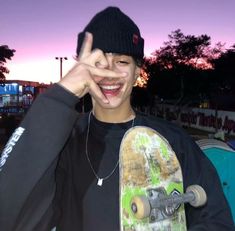 a young man is making the peace sign while holding his skateboard