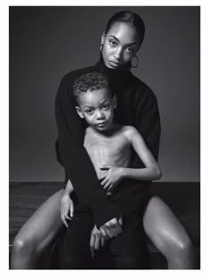 a black and white photo of a woman holding a boy in her lap, with the child's arm around him