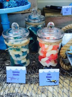 there are many different types of food in glass jars on the table with name tags