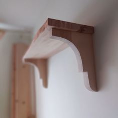 a wooden shelf mounted to the side of a wall next to a white painted wall