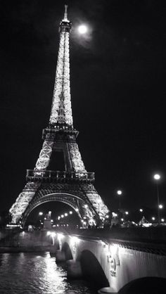 the eiffel tower lit up at night in black and white with lights on