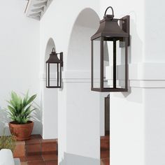 two lanterns on the side of a white building next to a potted green plant