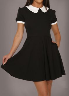 Channel your inner Wednesday Addams when you slip on this collar goth dress! This gothic dress stands out with its eye catching design that features white collar, fitted bodice, two side pockets and a short silhouette. The fitted bodice accentuates your curves, while the flowing skirt adds a touch of drama and elegance to your look. Whether you're a seasoned gothic fashionista or just love to make a bold statement with your style, this dress is sure to become a treasured piece in your wardrobe. Available in sizes US 4, US 6, US 8, US 10, US 12, US 14 and US 16. Made out of 95% polyester and 5% spandex. Fall in love with this goth dress the moment you put it on! Dress is sold without harness belt. Black Gothic Mini Dress With Short Sleeves, Black Gothic Knee-length Dress, Addams Dress, Wednesday Addams Dress, Gothic Black Dress With Doll Collar, Victorian Jacket, Gothic Dress With Ruffles And Doll Collar, Spring Gothic A-line Mini Dress, High Collar Dress