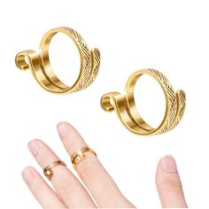 two pairs of gold rings on top of each other, with one being held up to the