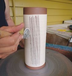 a person is working on a vase with holes in the center and thread running through it