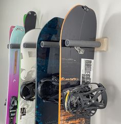 three snowboards are hanging on the wall next to each other and one is upside down