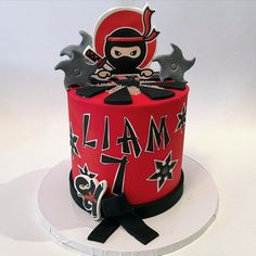 a red and black cake decorated with an image of a ninja on it's face