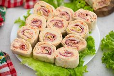 a plate filled with rolls on top of lettuce next to other food items