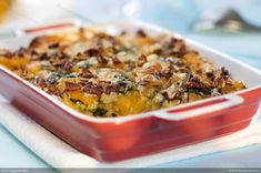 a red casserole dish filled with food on top of a blue table cloth