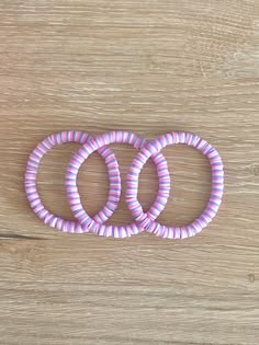 three pink and purple rings sitting on top of a wooden table