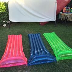 three inflatable pool floats sitting on the grass next to a white sheet covered tent