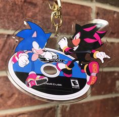 a keychain with an image of sonic and knuckles on it hanging from a brick wall