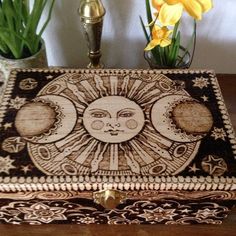 a decorative box sitting on top of a wooden table next to flowers and vases