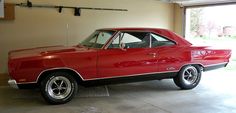 a red car parked in a garage next to a wall with an open door on it