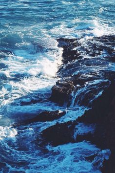 the waves are crashing on the rocks by the water