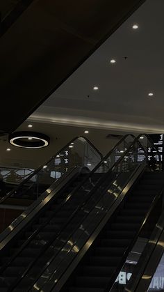 an escalator in a building with lights on the ceiling